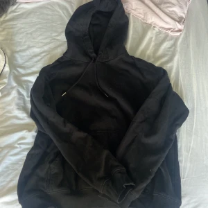 Svart hoodie  - En klassisk svart hoodie från H&M i storlek S. Tröjan har huva med snörning och en stor känguruficka framtill. Använd ett fåtal gånger.