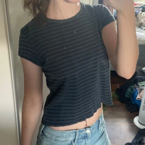 Brandy Melville Topp - Säljer en t-shirt med mörkblå och svarta ränder. Toppen har korta ärmar, rund halsringning och är tillverkad i ett mjukt bomullstyg. Perfekt till jeans eller kjol för en chill och avslappnad look speciellt nu till hösten💗Från Brandy Melville. Älskar denna topp men tyvärr kommer den aldrig till användning