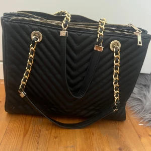 En rymlig fin väska säljes🩷 - Säljer en svart rymlig väska med guld detaljer på, den är i fint skick då den bara använts vid vissa tillfällen ❣️