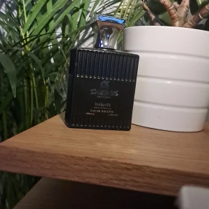 Spartacus Insignia Eau de Toilette 100ml - Maskulin parfym Spartacus Insignia Pour Homme, 100ml Eau de Toilette. Flaskan är svart med räfflad yta och har en snygg, silvrig metallkork. Designen är stilren och modern, perfekt för dig som gillar eleganta detaljer. En parfym som doftar som en elegant man. Fråga gärna frågor och är villig att gå ner i pris😁