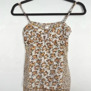 Blommig linnetopp med smala axelband - Supersöt linnetopp med blommigt mönster i gult. Toppen har smala axelband och en lätt rynkad detalj vid bysten. Perfekt för varma dagar och ger en romantisk vibe till din outfit.