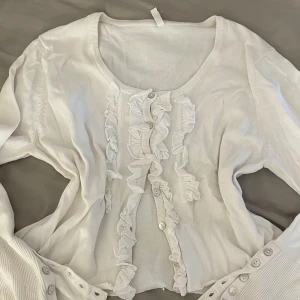 Vit kofta med volang och knappar - Supersöt vit kofta med volangdetaljer. 