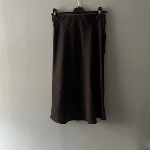 Svart långkjol från Lindex i storlek 146💕 - En svart långkjol från Lindex. Kjolen har en lätt glansig yta och rak passform som faller snyggt. Silkesmatrial som är väldigt luftigt och skönt att ha på sig. 💕