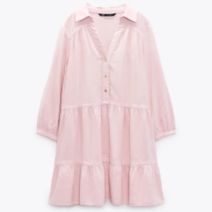 Ljusrosa kortklänning från Zara - Supersöt ljusrosa klänning från Zara i linneblandning. Klänningen har v-ringning med knappar samt trekvartsärmar med lätt puff och resår vid ärmslut. Perfekt för sommaren!