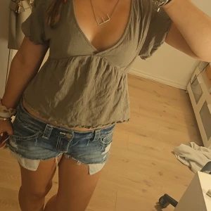 Beige omlottopp - Supersöt beige omlottopp från Lager 157 i storlek XS! Toppen har v-ringning, korta volangärmar och knyt i nacken. Den är croppad och har en flowy passform med lätt rynk nedtill. Perfekt för dig som gillar en avslappnad men trendig stil!! 💞💞