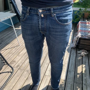 Morris jeans herr 30/33 – slim fit blå denim - Snygga jeans från Morris i storlek 30/33. Mörkblå tvätt med lätt slitning, rak/smal passform och klassiska detaljer som läderpatch bak i midjan. Mycket bekväma och sitter snyggt. Nypris ca 1800 kr, säljes för 200 kr. Endast sparsamt använda och i fint skick. Perfekt för både vardag och mer uppklädda tillfällen. Mitt pris endast 200kr!🤩Morris jeans, herrjeans, slim fit, straight fit, blå jeans, denim, herrmode, byxor, 30/33, mid rise, klassiska jeans, second hand, vintage denim, nypris 1800 kr 