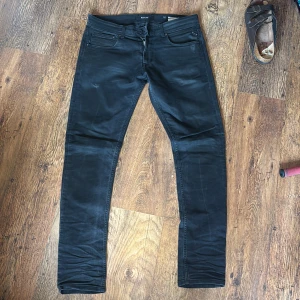 Replay jeans 34/34 - Säljer ett par svarta Replay som är modell johnfrus men sitter som anbass och de är storlek 34/34. På bild tre ser man att jag gjort två slitningar som är helt okej bra därav priset. 