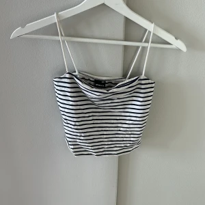 Randig linnetopp från Gina Tricot - Supersöt randig linnetopp från Gina Tricot i vitt och marinblått. Toppen har tunna axelband och croppad passform, perfekt för varma dagar. Mjuk och lätt bomullskänsla som gör den riktigt skön att bära.