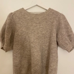 Beige stickad tröja från Vero Moda - Supermysig beige stickad tröja från Vero Moda med korta puffärmar och rund hals. Tröjan har en ribbad struktur och är perfekt att styla med jeans eller kjol. Den är i storlek m men har passat bra på mig som är xs/s