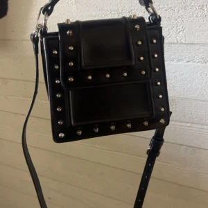 Svart väska från zara - Säljer denna fina väska från Zara för jag inte fått använign för den tyvärr. Den är ca 20 cm bred och ca 20 cm hög med!