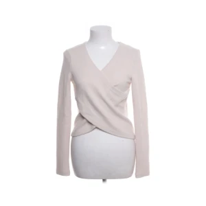Beige omlottopp med v-ringning - Superfin beige omlottopp med v-ringning och långa ärmar. Toppen har en snygg omlottdesign framtill som ger en cool och trendig look. Perfekt att styla med jeans eller kjol för en enkel men chic outfit. Sitter mer som en xs. Priset kan diskuteras vid snabb affär.