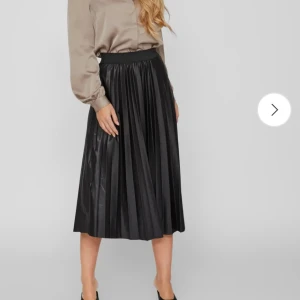 Svart  långkjol från Vila - Snygg svart  långkjol från Vila med glansig finish och bred resår i midjan. Osäker på storlek men skulle gissa på XS eller S. Använd fåtal gånger.