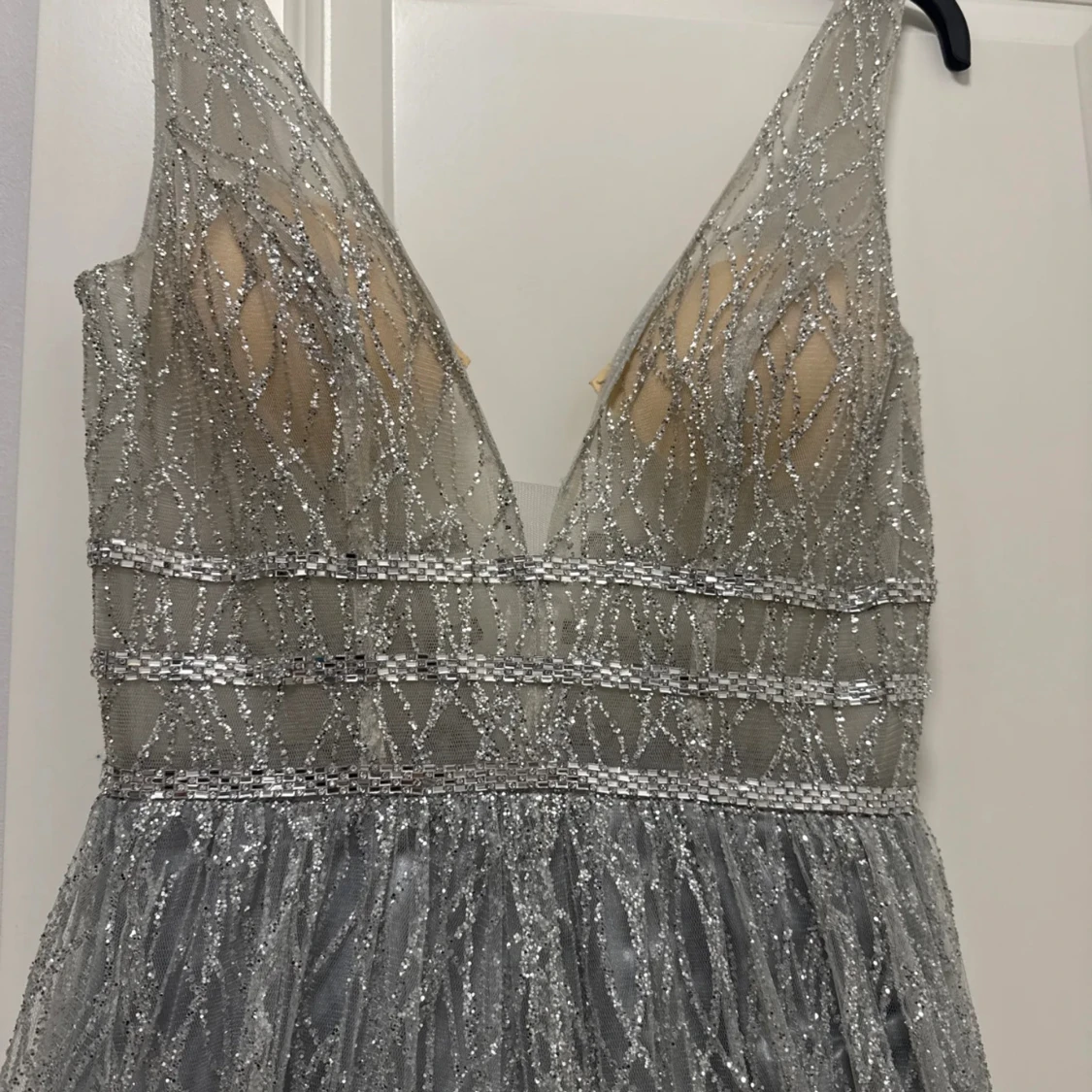 Kimalteleva hopeanvärinen pitkä mekko, jossa syvä v-pääntie - 1