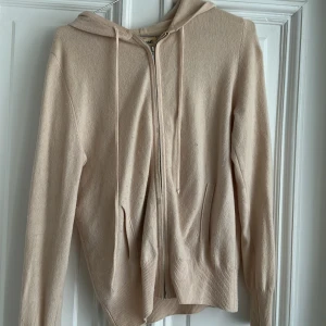 Ljusrosa kashmirhoodie med dragkedja Soft Goat - Beige hoodie från Soft Goat i mjuk stickad kvalitet. Ganska sliten och har en söm som lossnat lite vid dragkedjan. Tror den hade fått ett lyft med kashmir tvätt och eventuell hemmalagning av sömmen. 