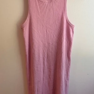 Rosa ribbad klänning från H&M - En enkel och snygg rosa ribbad klänning från H&M. Ärmlös modell med rund halsringning och rak passform. Perfekt för varma dagar och lätt att styla med sneakers eller sandaler.