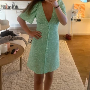 Mintgrön kortklänning med v-ringning - Superfin mintgrön klänning med vitprickigt mönster och djup v-ringning. 