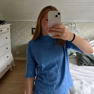 Blå polotopp med halvlånga ärmar - Säljer en blå polotopp med halvlånga ärmar och rak passform. Toppen har en enkel och stilren look med ribbad krage och är tillverkad i mjukt material. Perfekt att styla med jeans eller kjol för en chill vibe. Är i storlek M men skulle säga att den passar som en Xs/S .