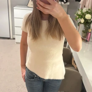Stickad Zara topp med snörning - Superfin beige topp med korta ärmar och asymmetrisk nederkant. Baksidan är snörning som man kan justera. Använd nån gång