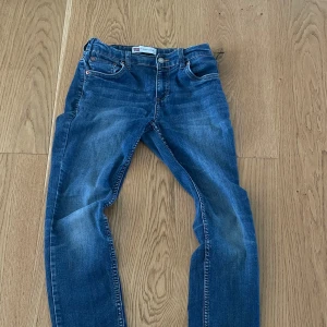 Levi's 512  blå jeans slim fit - Snygga blå Levi's 511 jeans med klassisk femficksdesign och smal passform. Jeansen har en lätt tvättad look med slitningar på knän och benslut. Perfekta för dig som gillar en modern och stilren vibe. Ikonisk röd Levi's-tag på bakfickan.