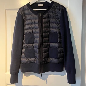 Mörkblå Moncler pufferjacka - Snygg mörkblå Moncler cardigan. Säljer denna pgd av att jag inte har använt den alls mycket än vad jag trodde den skulle användas. Inga defekter eller skador. För fler bilder skriv eller annan information om själva jackan äkthets bevis osv.. Jag är en tjej på 170cm lång. Brukar ha strl S/M i vanliga jackor. Men eftersom deras moncler cardigan är mindre i strl behövde jag ha L. Kvitto,prislapp och allt är kvar.