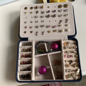 Mix av örhängen och armband - Säljer ett stort set med örhängen i olika former och färger, bland annat svarta studs, blommor, snögubbar och julstrumpor samt ett glittrigt mörkblått armband med gulddetalj. Perfekt för dig som vill variera din stil med både söta och roliga smycken. Priser diskuteras 