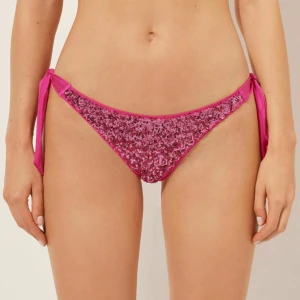 Calzedonia bikiniunderdel - Snygg bikiniunderdel i starkt rosa med glittriga paljetter framtill och knyt i sidorna. Bikinin har en klassisk tanga-modell och är perfekt för strandhäng. Materialet är troligtvis syntet för bästa passform och komfort. 