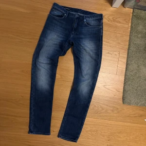 Emporio Armani jeans - Snygga blå jeans från Emporio Armani med klassisk femficksdesign och diskret logga på bakfickan. Jeansen har skinny passform och är tillverkade i mjukt bomullstyg med stretch för extra komfort. Perfekta för dig som gillar en smal siluett och stilren look. Pris kan diskuteras