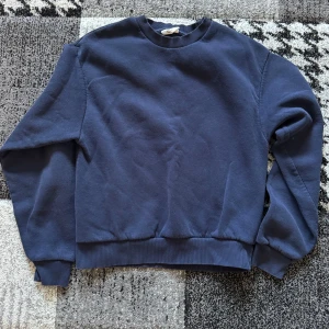 Mörkblå basic sweatshirt från Gina  - Enkel och stilren mörkblå sweatshirt med rund halsringning och ribbade muddar vid ärmslut och nederkant. Perfekt för en avslappnad look och lätt att matcha med jeans eller joggers.