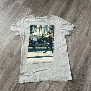 Grå Looney Tunes t-shirt MOXPLOSION XS - Grå t-shirt från MOXPLOSION i samarbete med Looney Tunes. Framsidan har ett stort tryck med Bugs Bunny och Daffy Duck och texten #YouGottaBeKiddin. Rund hals och korta ärmar, tillverkad i mjuk bomull. Perfekt för dig som gillar coola prints och klassiska cartoon-vibes.