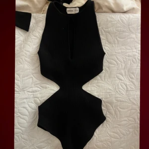 Svart body med utskärningar - Snygg svart body med utskärning vid höfter och vid bröstet. Aldrig använd. 