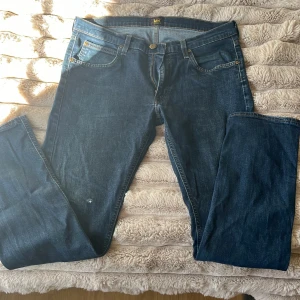 Lee Daren Zip Fly jeans blå W34 L32 - Säljer ett par klassiska Lee Daren Zip Fly jeans i mörkblå denim. Modellen har raka ben, fem fickor och snygga kontrastsömmar. 