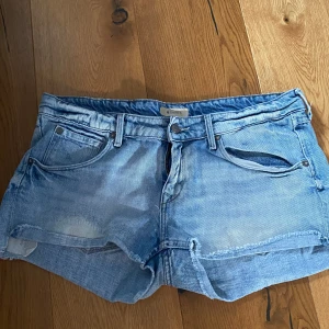 jeansshorts - Snygga blå jeansshorts med klassisk femficksdesign och knappgylf. Perfekta för en avslappnad stil. De har en ljus tvätt och är tillverkade i slitstarkt denim.
