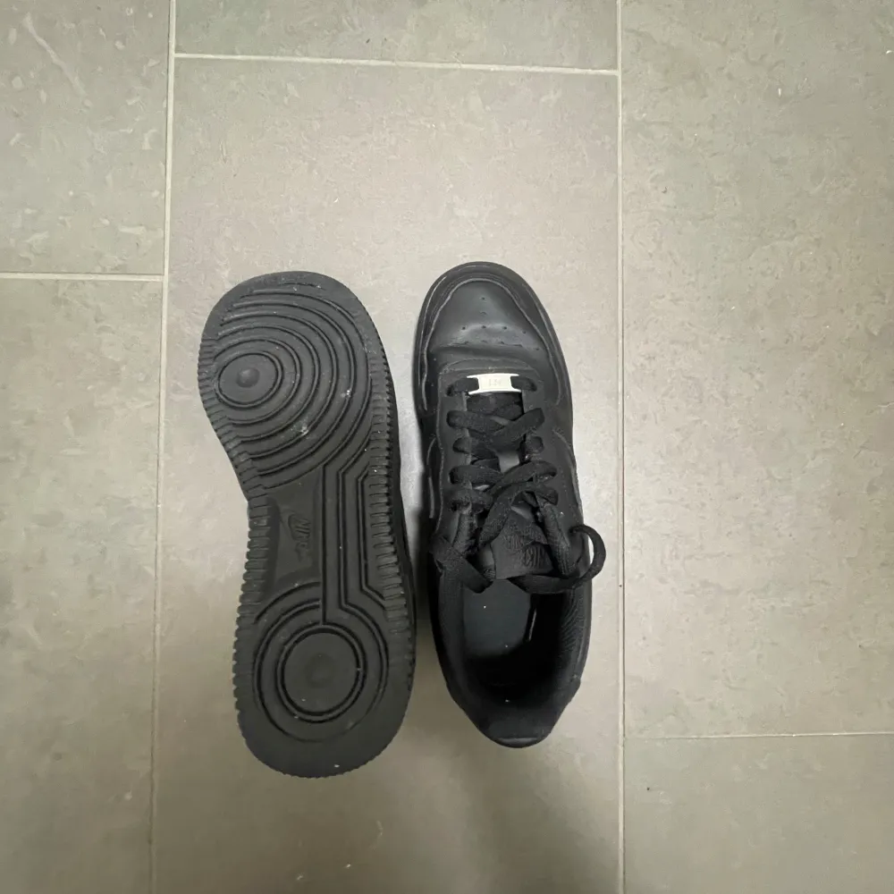Snygga svarta Nike Air Force sneakers med klassisk design. Skorna har en robust sula och snörning framtill. Perfekta för en stilren look.. Kengät.