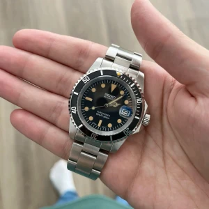 Seiko Submariner Vintage Mod - Inspirerad av den ikoniska Submariner-designen och utrustad med Seiko NH35 automatisk rörelse, är Seiko Mod Submariner en 40 mm klocka som kombinerar lyx och tillgänglighet.  Funktioner: • Diameter: 40 mm • Rörelse: Seiko NH35 automatisk • Tjocklek: 12 mm • Glas: Safir, rep-resistent • Luminova: Ja • Fall: 316L rostfritt stål • Krona: Skruvad • Armband: 316L rostfritt stål • Vattentålig: 3 ATM