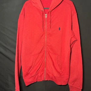 Ralph Lauren huvtröja med dragkedja| Röd| Regular | Stl L - Läs nedan för mer info!😊  Säljer en snygg röd hoodie från Ralph Lauren med dragkedja och broderad logga på bröstet. Den har en klassisk design med långa ärmar och en praktisk huva. Perfekt för en avslappnad stil.  Produktinformation:  ✅ Märke: Ralph Lauren  ✅ Storlek: L ✅ Färg: Röd ✅ Material: Bomull ✅ Passform: Regular  ✅ Skick: Mycket bra skick, knappt använd  Frakt och betalning: 📦 Snabb leverans – skickar inom 1-2 dagar efter beställning📦
