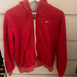 Röd hoodie från Nike - Super snygg Nike hoodie med vit dragkedja. Väl använd med inga defekter. Storlek L men skulle säga att den är mer en M.🤍