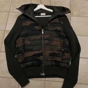 Sällsynt Moncler cardigan  - Snygg jacka från Moncler med camouflage-mönster och stickade ärmar. Jackan har en dragkedja framtill och en huva för extra skydd. Perfekt för en cool och avslappnad stil. jackan är en limiter edition jacka från Asien som bara Monclers högsta kunder kunnat köpa.