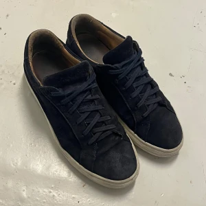 Mörk blå  sneakers från A DAY’S MARCH  - Snygga blå sneakers i mocka från A DAY’S MARCH med vit sula och snörning. Perfekta för en stilren look. Dom är ganska använda men var länge sen jag använde dom nu. Ord pris 1800, skicka cirka 6/10. Mockan är lite sliten men inte som syns när man använder dom. Hör av vid frågor. Passar 41-42