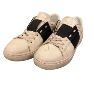 Valentino Open - Snygga Valentino Garavani sneakers i vitt med en marinblå detalj över sidan. Skorna har snörning och är perfekta till sommaren och våren‼️De kommer i originalförpackning. Dem har tecken på användning och skulle behövas städas lite men annars fungerar dem helt perfekt. Riktigt bra pris‼️Kom med frågor och prisförslag😇