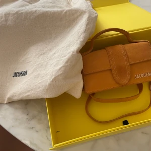 Orange  axelväska från Jacquemus - Nästan oanvänd orange mini väska från Jacquemus med ett stilrent och kompakt design. Väskan har en justerbar axelrem och ett handtag för enkel bärning. Kvitto finns på 490 Euro ca 5700 SEK 