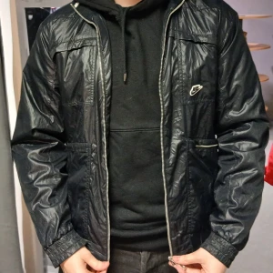 Svart vindjacka från Nike - Säljer en svart vindjacka från Nike. Jackan har långa ärmar och två fickor. Tunt tyg så det är bra att ha nu till våren och sommaren 