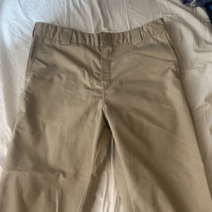 Beige byxor från Carhartt WIP - Säljer ett par stilrena beige byxor från Carhartt WIP. Byxorna har en klassisk design med normal passform och är tillverkade i en bomulls- och polyesterblandning. Perfekta för en avslappnad look. Nypris är cirka 1000kr