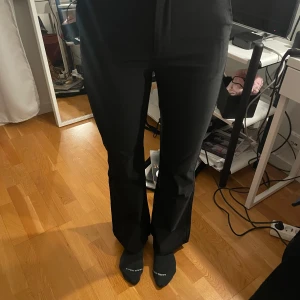 Svarta byxor från Gina Tricot - Snygga svarta byxor från Gina Tricot med bootcut-stil. Perfekta för en stilren look. Byxorna har en klassisk design med en smickrande passform.