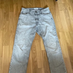 Grå jeansbyxor - Snygga grå jeansbyxor med klassisk femficksdesign. De har en rak passform och är perfekta för en avslappnad stil. Byxorna har en knapp och dragkedja framtill.