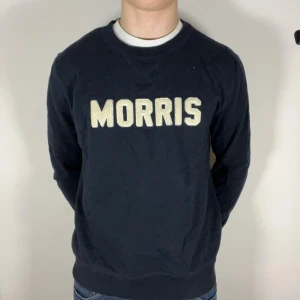 Morris sweatshirt - Säljer en mörkblå sweatshirt från Morris med stora vita bokstäver på bröstet. Tröjan har en klassisk rund halsringning och långa ärmar. Perfekt för en avslappnad stil. Lite stor på mig som är 178, 74 kg