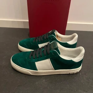 Gröna Valentino flycrews - Snygga gröna sneakers i mocka från Valentino med vita detaljer och svarta snören. Skorna har en stilren design med nitar på hälen och en vit sula. Perfekta för en trendig look.