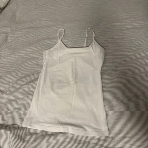 Vit linnetopp - Säljer en enkel och stilren vit linnetopp med smala axelband. Perfekt för varma dagar eller som lager under andra plagg. Passar till många olika stilar och tillfällen.