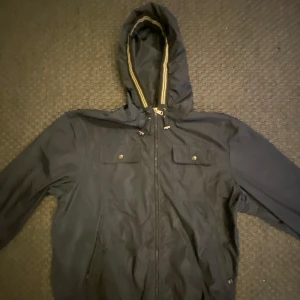 Svart vindjacka från Moncler - Säljer en stilren svart vindjacka från Moncler med huva och dragkedja. Jackan har två bröstfickor med knappar och ett Moncler-märke på ärmen. Perfekt för blåsiga dagar och för sommaren.Pris kan diskuteras vid snabb affär🤑🍾🔥