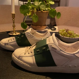 Gröna Valentino opens  - Snygga Valentino Garavani sneakers i skick 8/10, det är lite snören som sticker ut men de går bra! . Skorna har en stilren design med snörning och en bred grön rem över ovansidan. Perfekta för en trendig look. Jag e intresserad av byten också 👍🏻👍🏻✅✅, hör av er om ni har frågor eller funderingar 😃 box o kvitto ingår tyvärr inte men de är äkta!