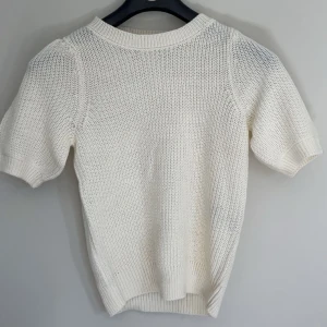 Vit stickad kortärmad tröja - Snygg vit stickad tröja med korta ärmar och ribbade muddar. 